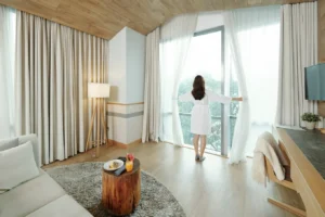 kobieta rozsuwająca zasłony w oknie apartamentu